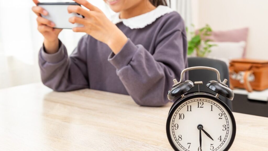 スマートフォンを長時間使用する子どもと時間のイメージ